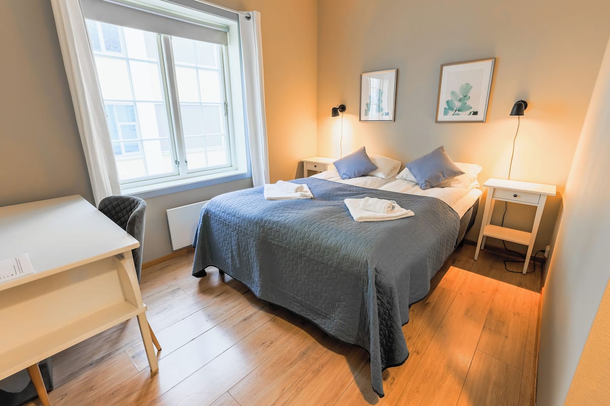 Ein Schlafzimmer mit Bett, Nachttischen, einem Schreibtisch und einem Fenster.