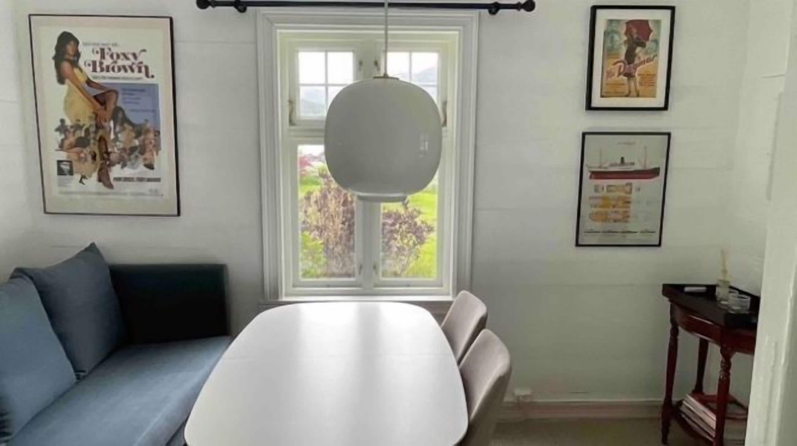 En matplats med ett vitt bord, en blå soffa och en hängande lampa.