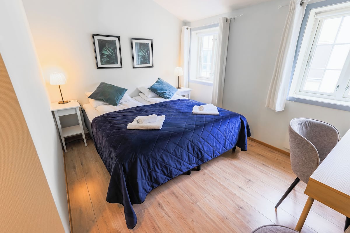 Ein Schlafzimmer mit einem Bett, Nachttischen, einem Sessel und einem Fenster.