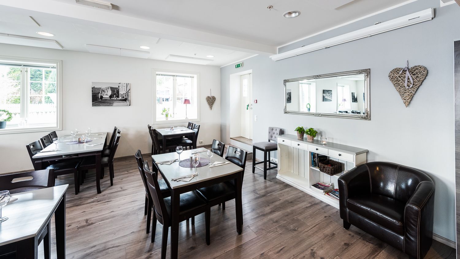 A dining area with a table set for four, a sofa, and a cabinet with decorative items.