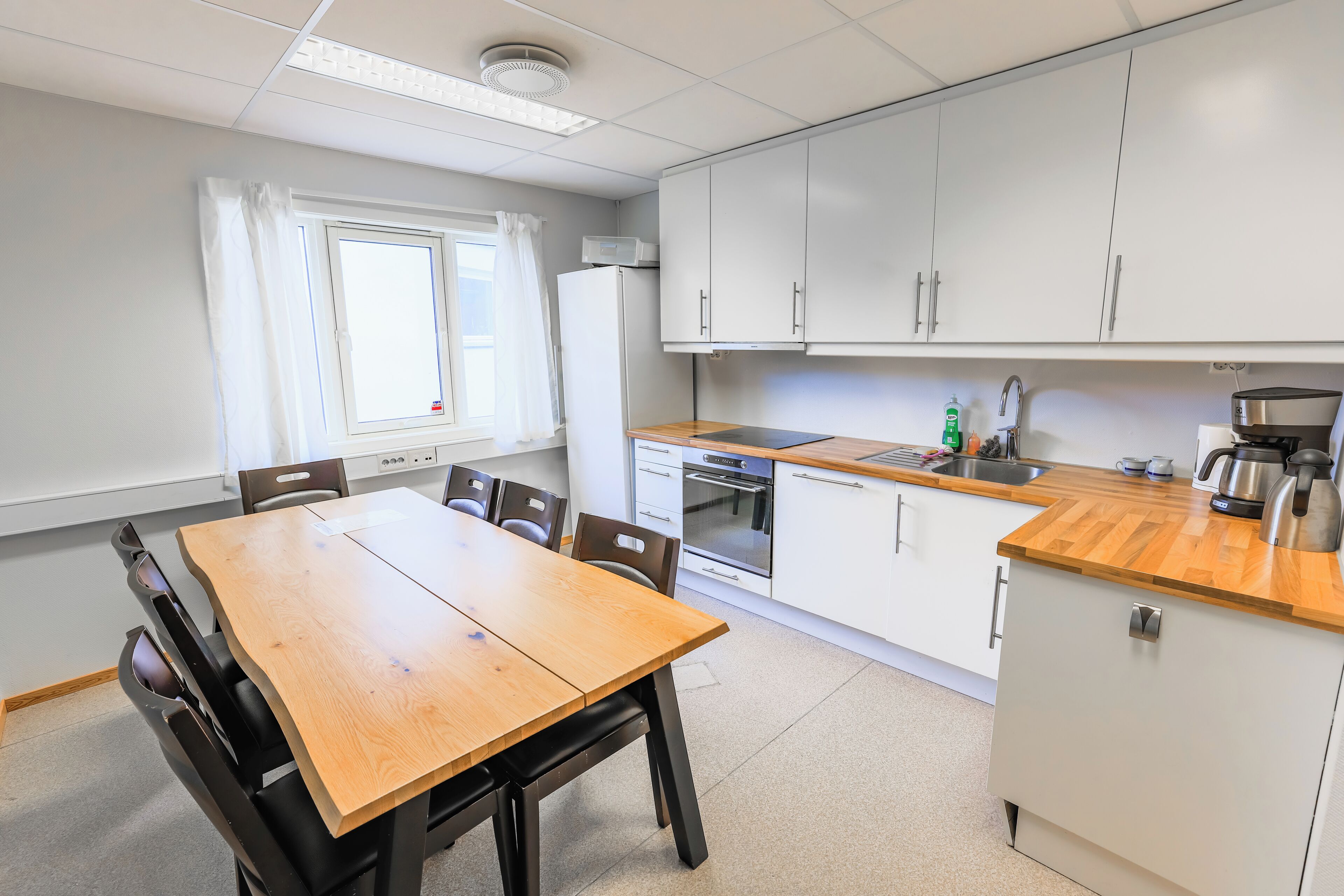 Una cocina moderna con armarios blancos, encimera de madera y una zona de comedor con mesa y sillas.