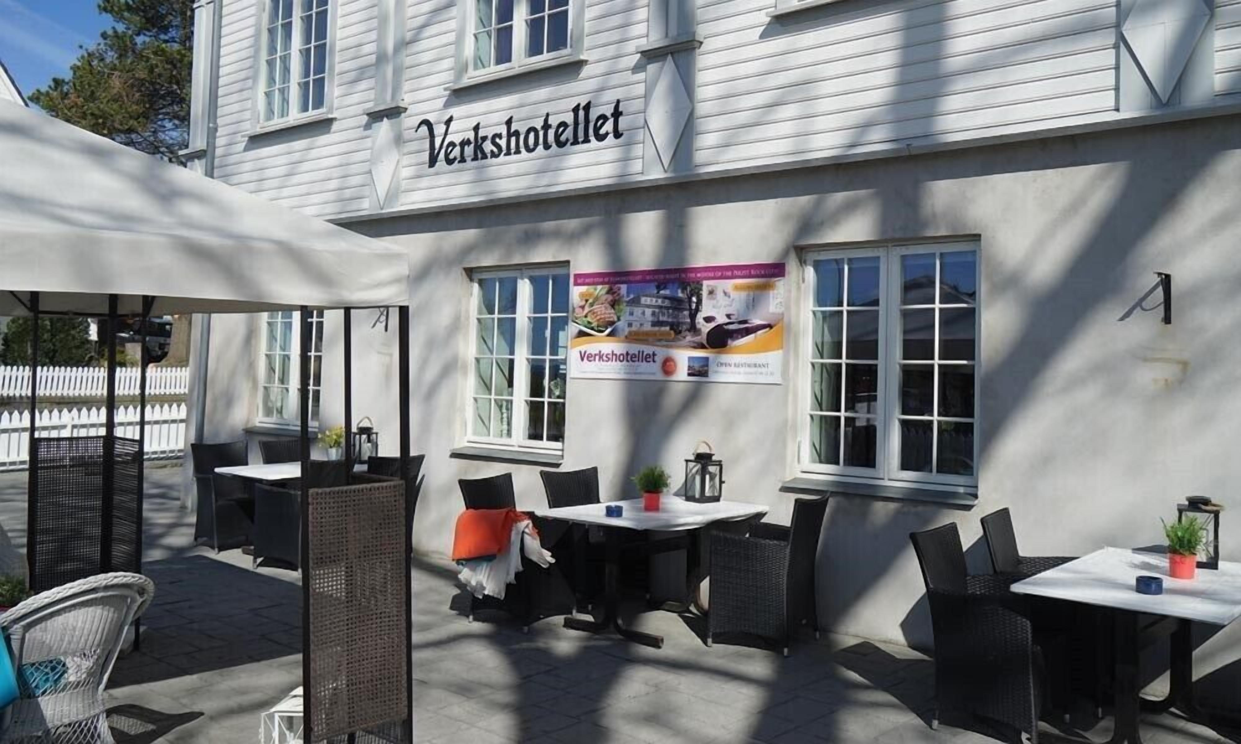 An outdoor seating area with tables and chairs, a sign reading "Verkshotellet", and a banner advertising the restaurant.