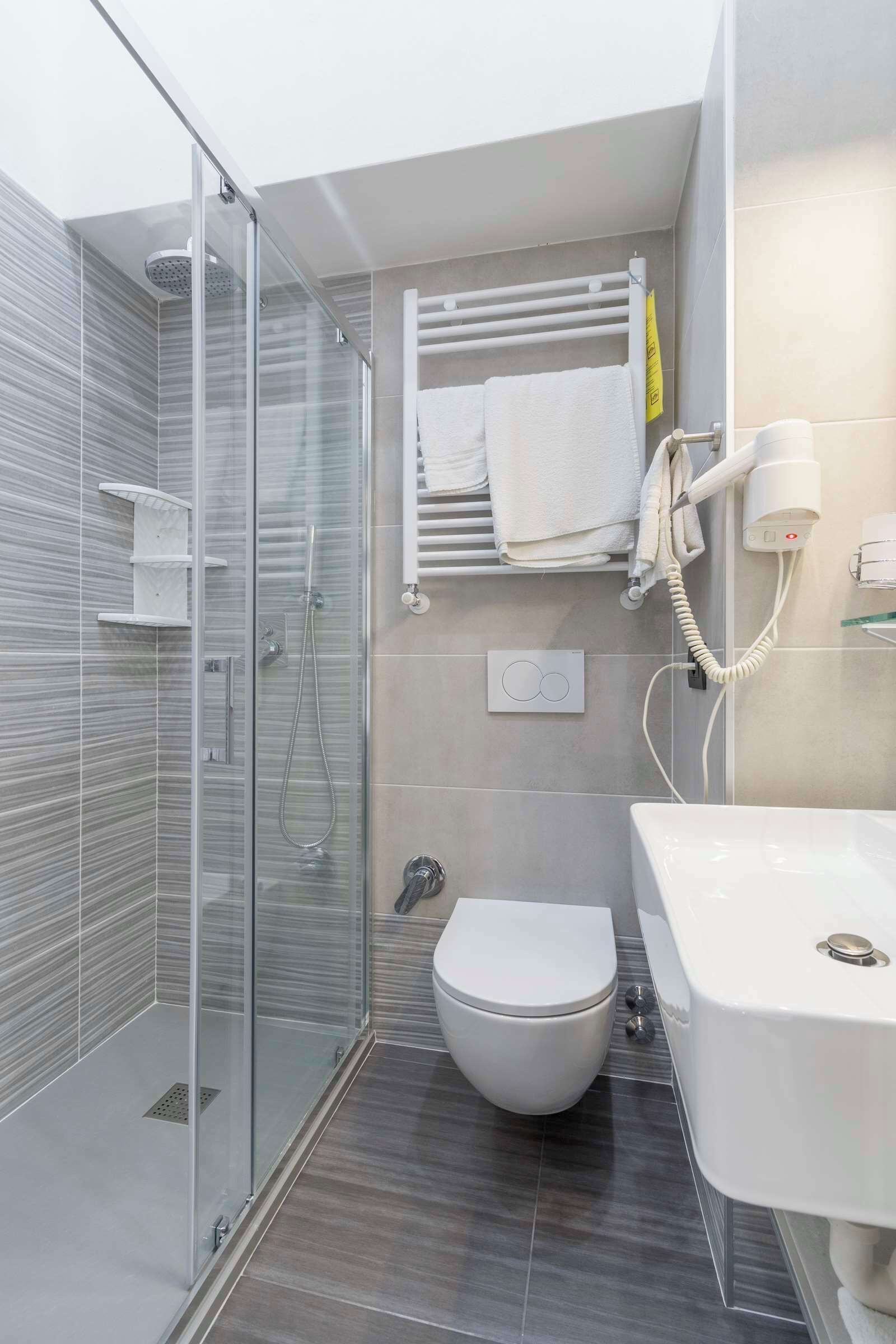 A modern bathroom with a glass-enclosed shower, a toilet, and a sink.