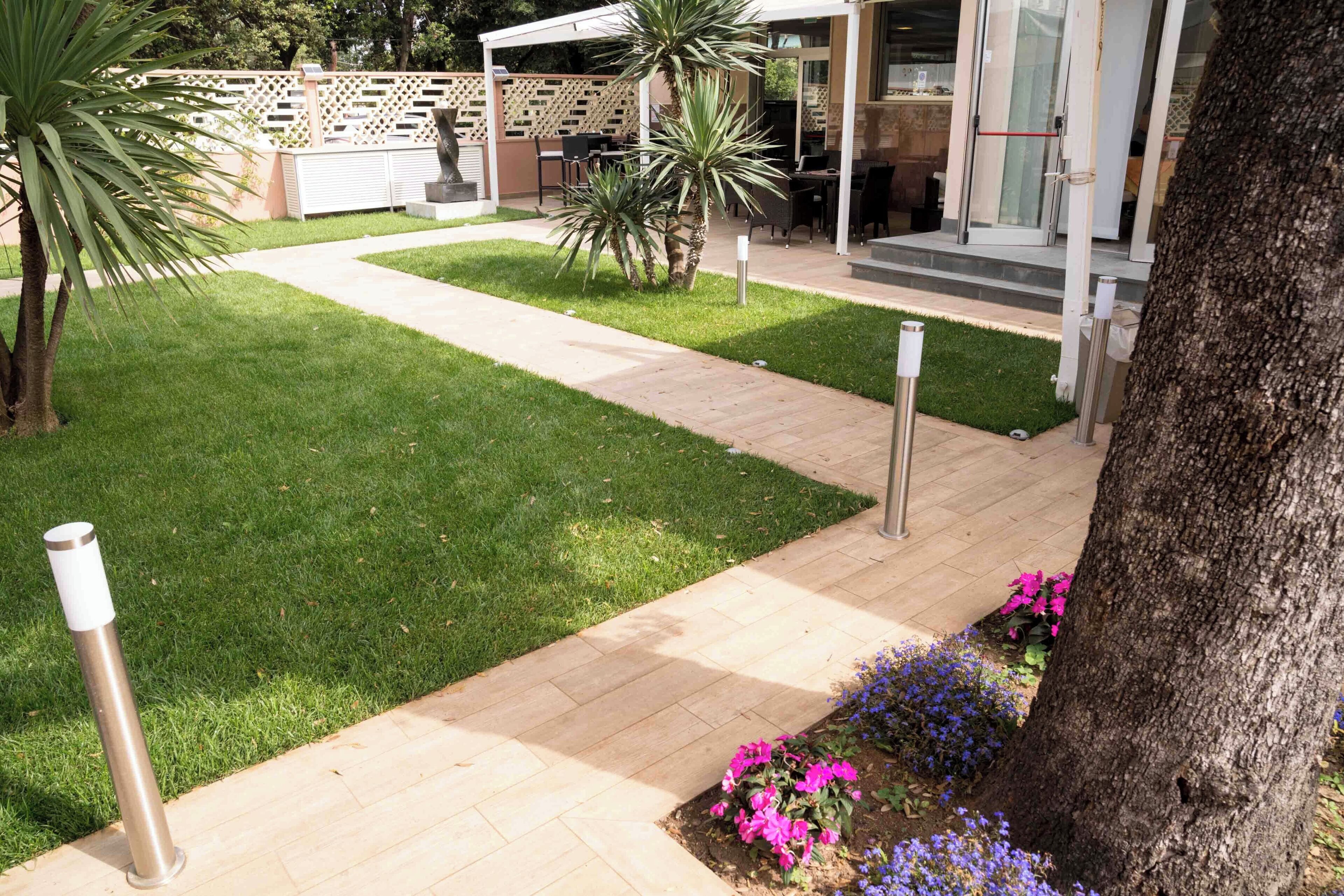Ein gepflegter Garten mit befestigtem Weg, einer Sitzgelegenheit und einer überdachten Terrasse.
