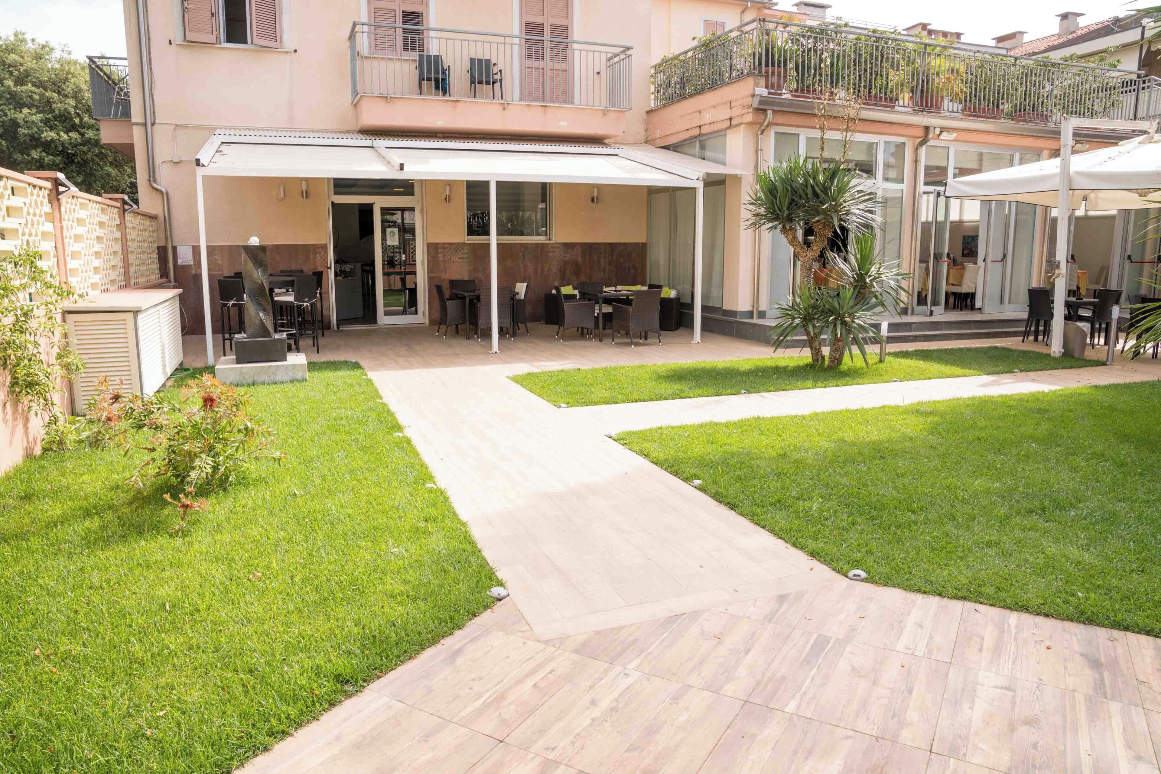 Une cour avec des espaces de détente en plein air, un patio couvert et une pelouse bien entretenue.
