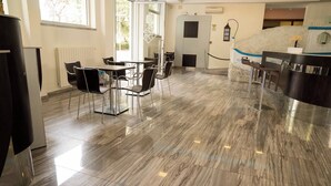 A modern hotel lobby with a marble floor, a reception desk, and a seating area with chairs and tables. - Hotel Roma (Massa)