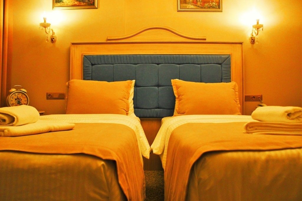 A hotel room with two beds, each with a blue headboard, and a wooden headboard in the center.
