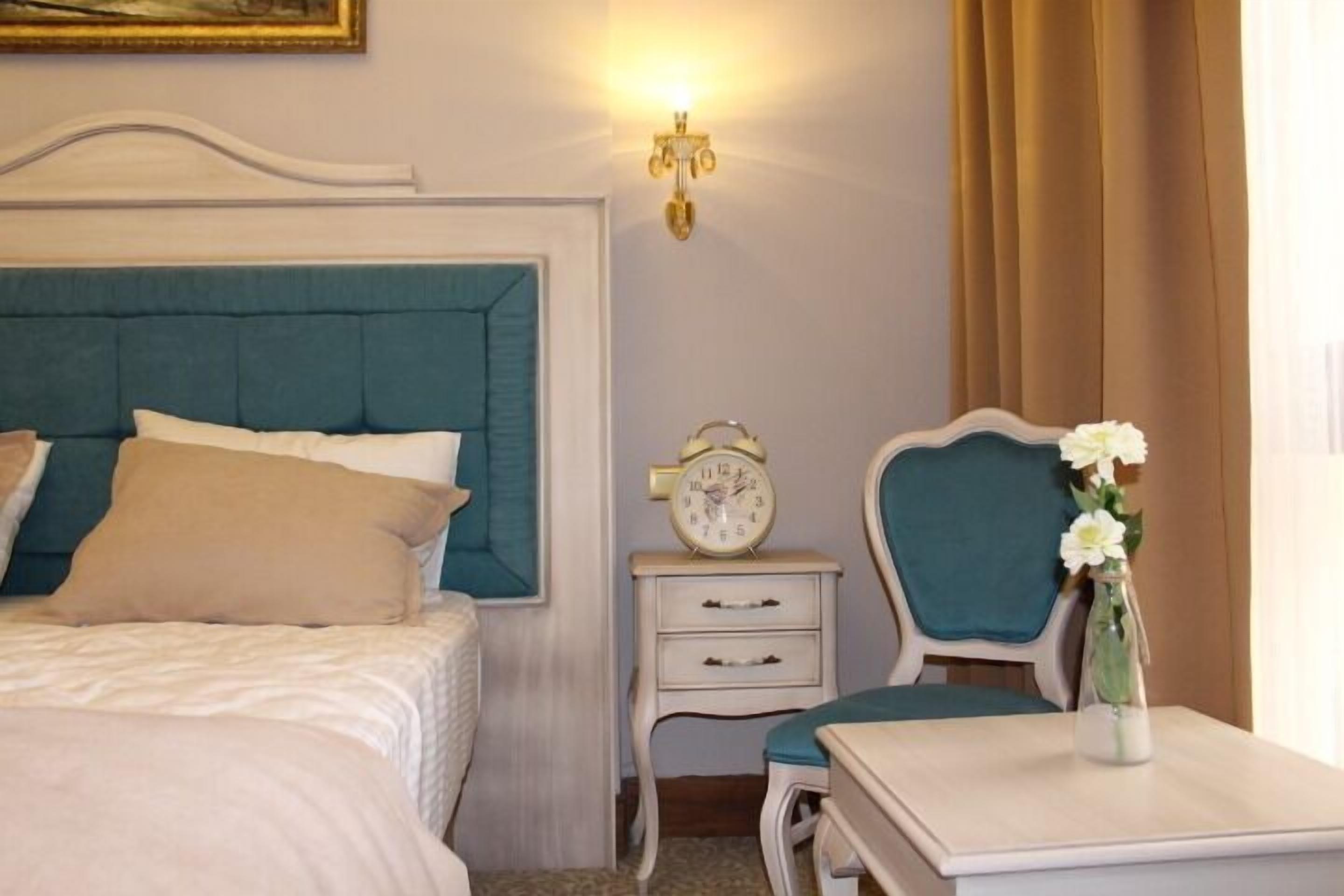 Ein ordentlich eingerichtetes Schlafzimmer mit Bett, Nachttisch, Stuhl und einer Wanduhr.