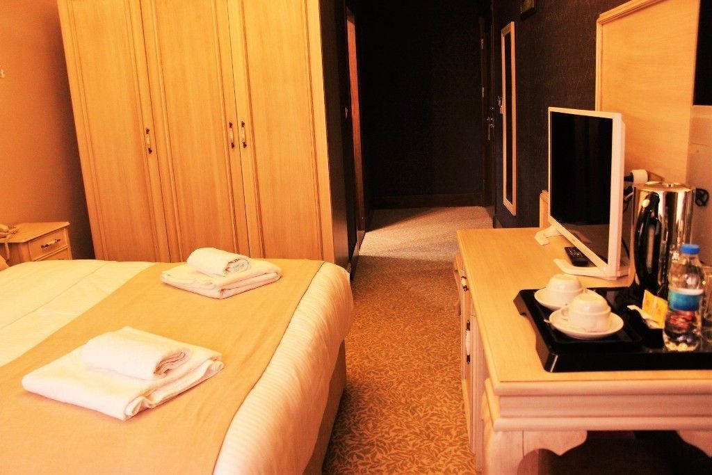 Une chambre d’hôtel avec deux lits, un bureau avec un ordinateur et un plateau avec une bouteille et des verres.