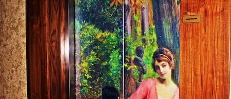 Un ascensor con un mural de una escena boscosa y una mujer con vestido.