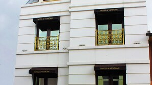 Un edificio de varios pisos con balcones que presentan barandillas de metal ornamentadas y ventanas con la leyenda