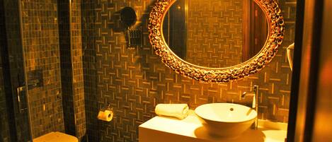 Un baño con un lavamanos blanco, un espejo redondo con un marco decorativo y un inodoro.