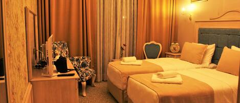 A hotel room with two beds, a desk, a chair, and a painting on the wall.
