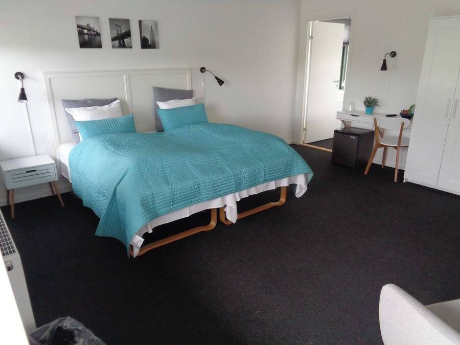 A bedroom with a bed, bedside tables, a desk, and a chair.