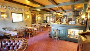 Un restaurante con vigas de madera, una zona de bar y una alfombra estampada.