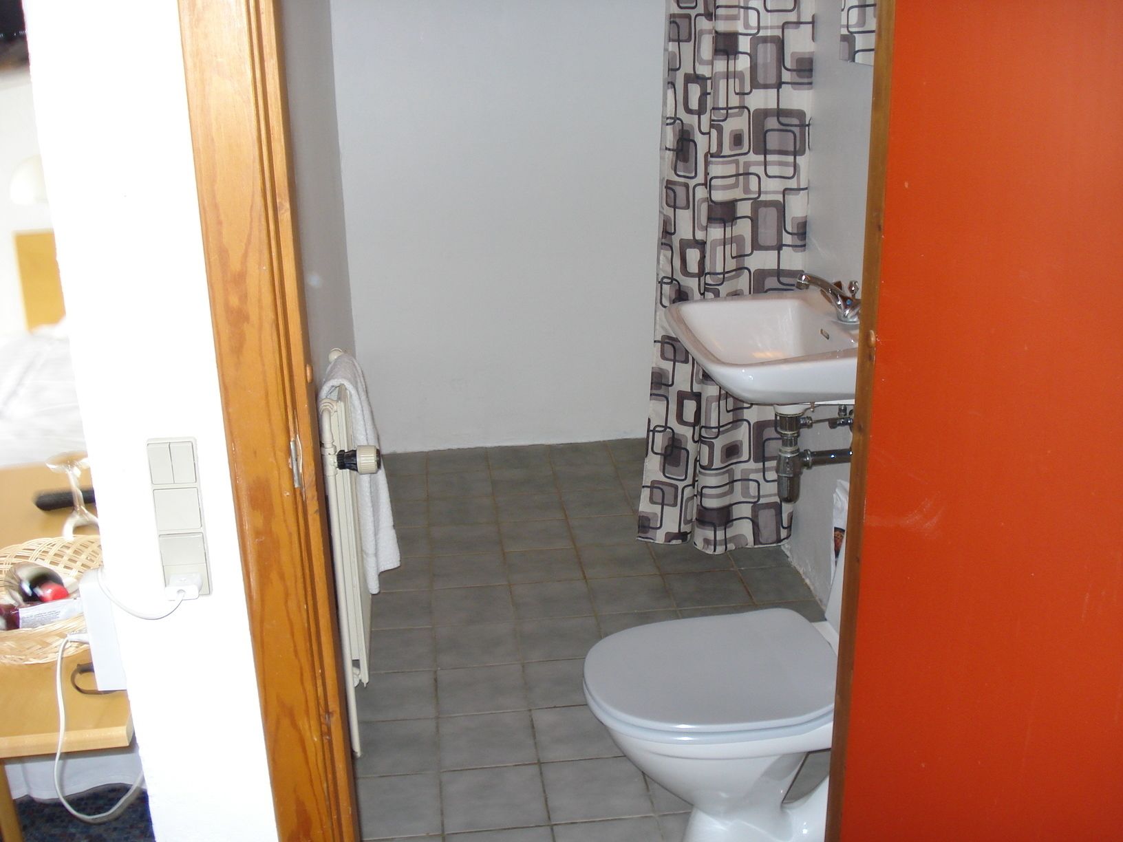 A small bathroom with a toilet, a sink, and a shower curtain.