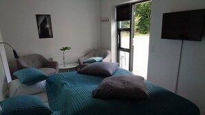Un dormitorio con cama, una silla, una mesa y una ventana.