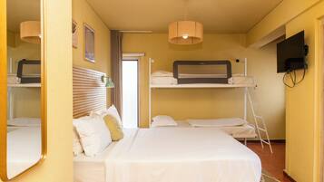 Habitación de hotel con literas, televisor de pantalla plana, espejo y ventana con cortinas.