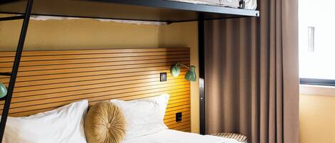 Quarto com beliche, cabeceira de madeira, luminária de cabeceira e janela com cortinas.