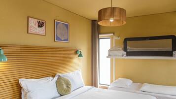 A hotel room with a wooden headboard, two beds, a hanging light fixture, and artwork on the wall.