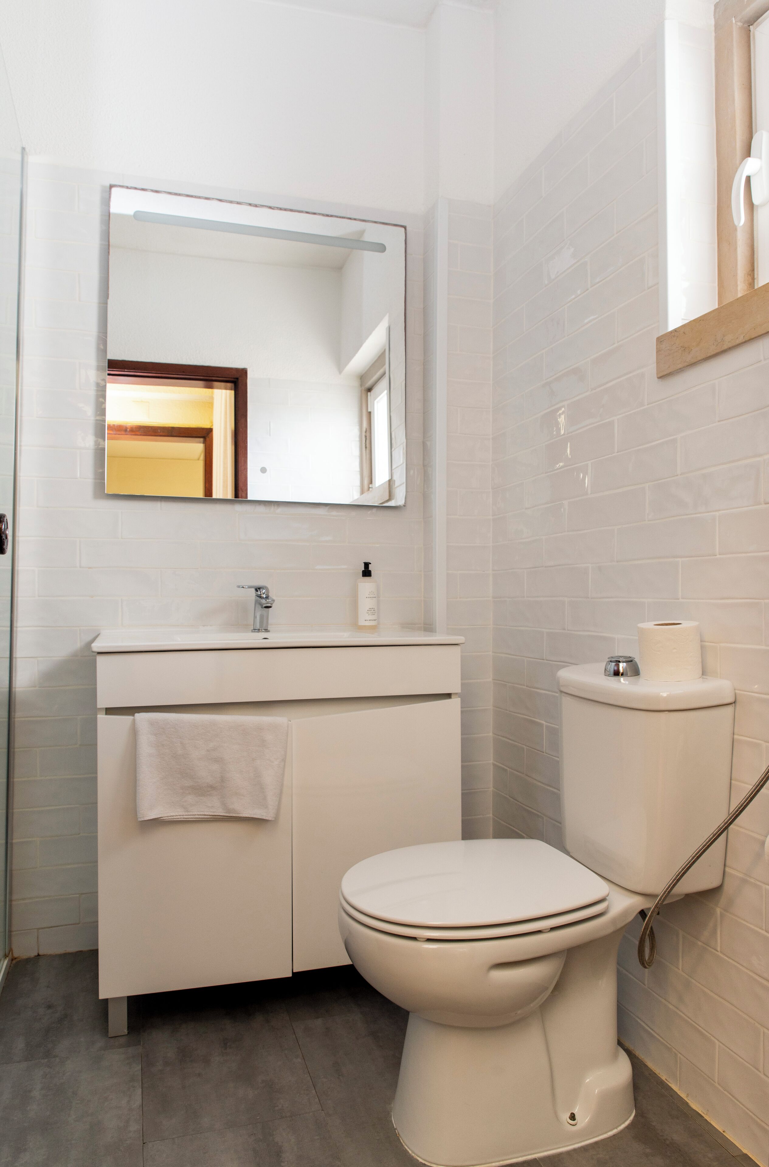 Un baño con lavamanos, espejo y inodoro blancos.