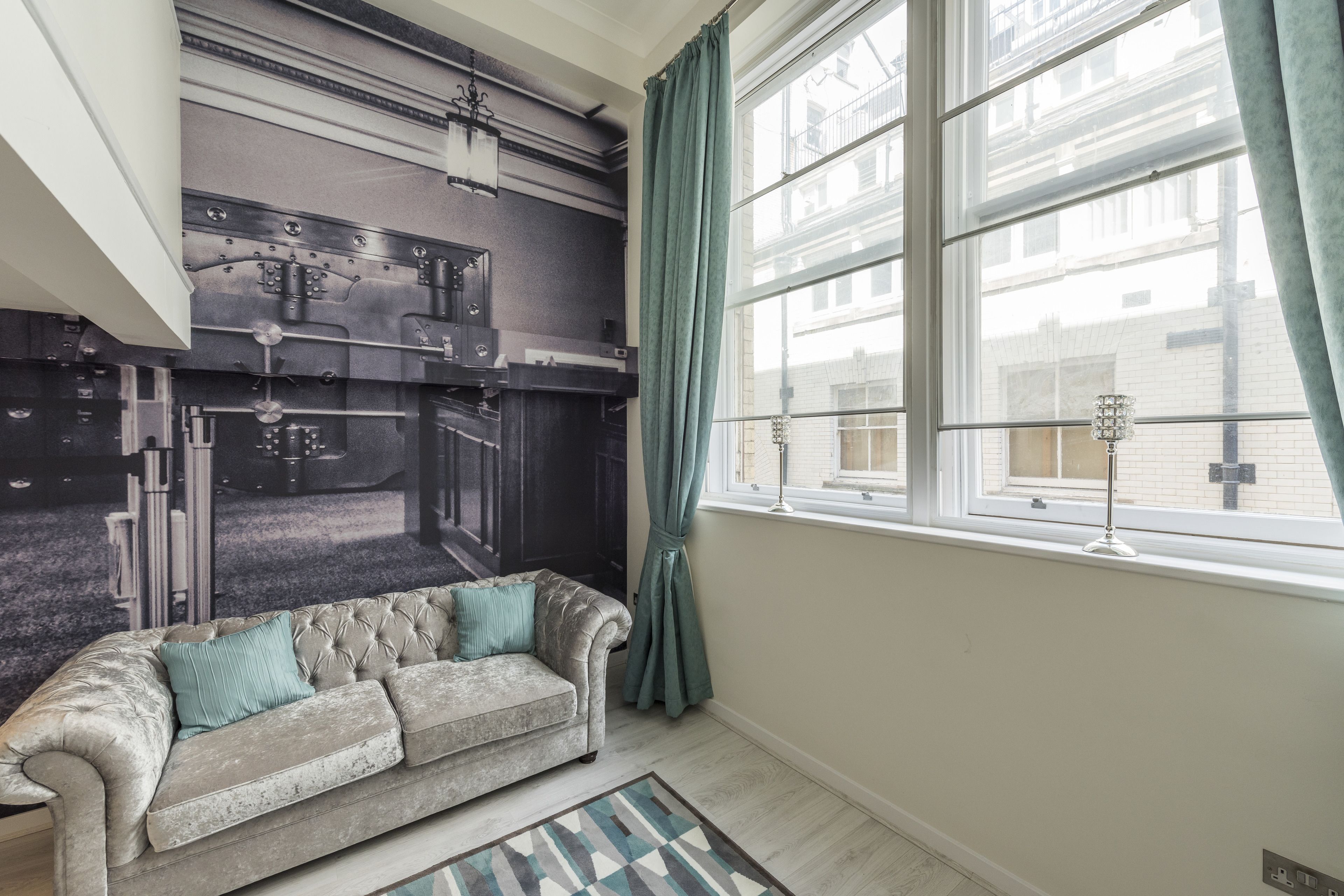 Een kamer met een groot raam, een bank en een radiator aan de muur.