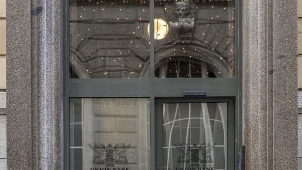 L’entrée d’un immeuble, avec une façade en pierre et une porte en verre sur laquelle est affiché le logo de l’Union Bank.