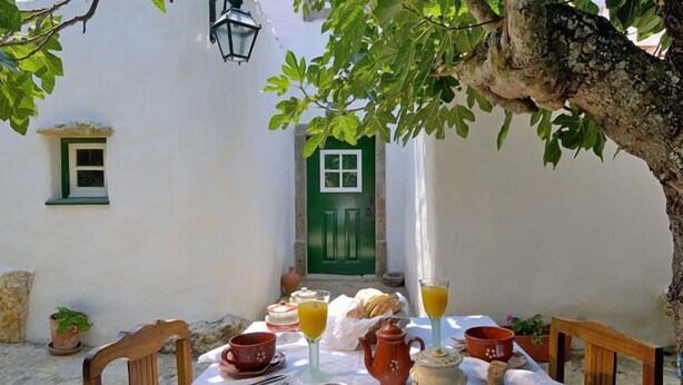 A table set for breakfast with a view of a white building and a green door. - Aldeia da Mata Pequena (Mafra)