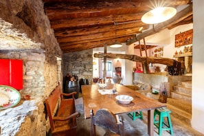 Un coin repas rustique avec une table en bois, des bancs et un mur en pierre.