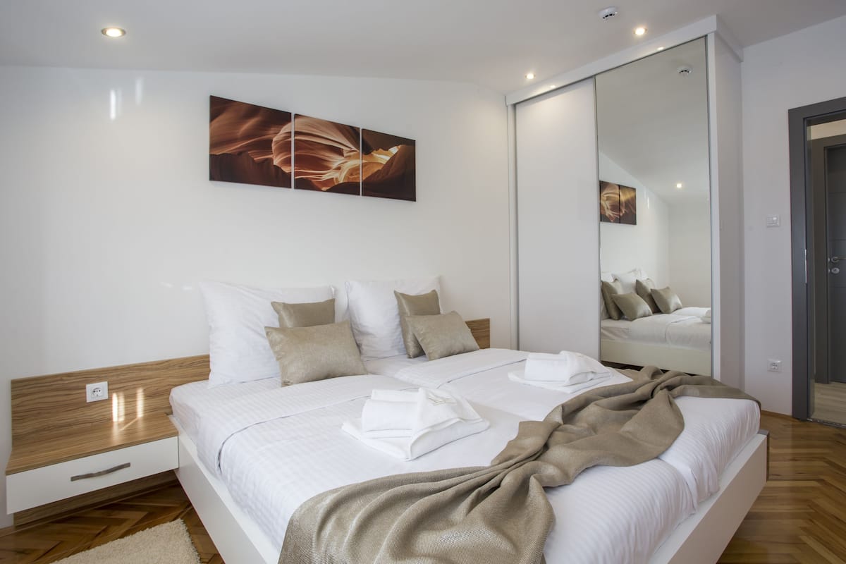 Un dormitorio moderno con una cama grande, una mesita de noche, un espejo y un cuadro en la pared.
