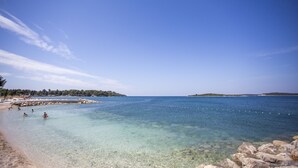 A clear beach with rocky shorelines and calm waters. - Adrion Aparthotel (Pula)