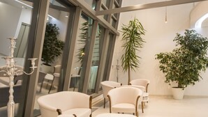 A modern interior with white furniture, large windows, and potted plants. - Adrion Aparthotel (Pula)