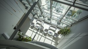 A modern interior with a glass ceiling, white walls, and seating areas. - Adrion Aparthotel (Pula)