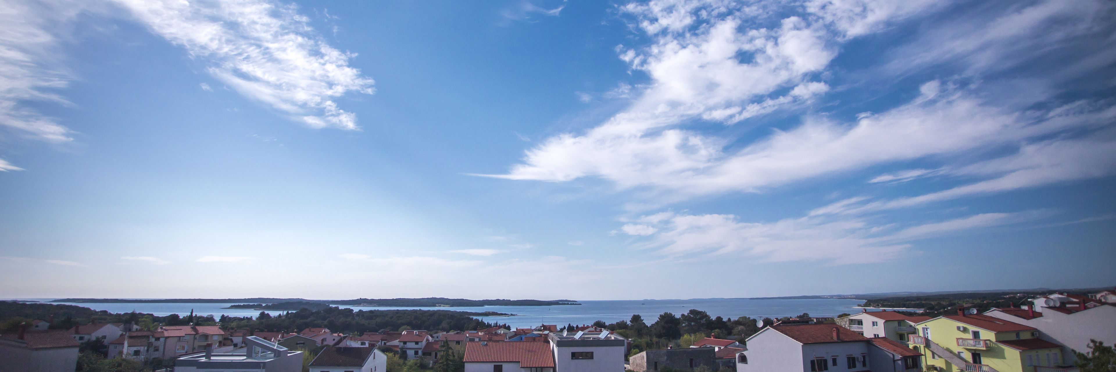 Une ville côtière avec des maisons, un ciel dégagé et une étendue d’eau à l’horizon.