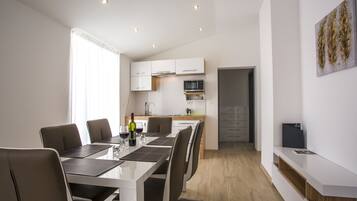 A modern kitchen with white cabinets, a microwave, and a wine bottle on the counter.