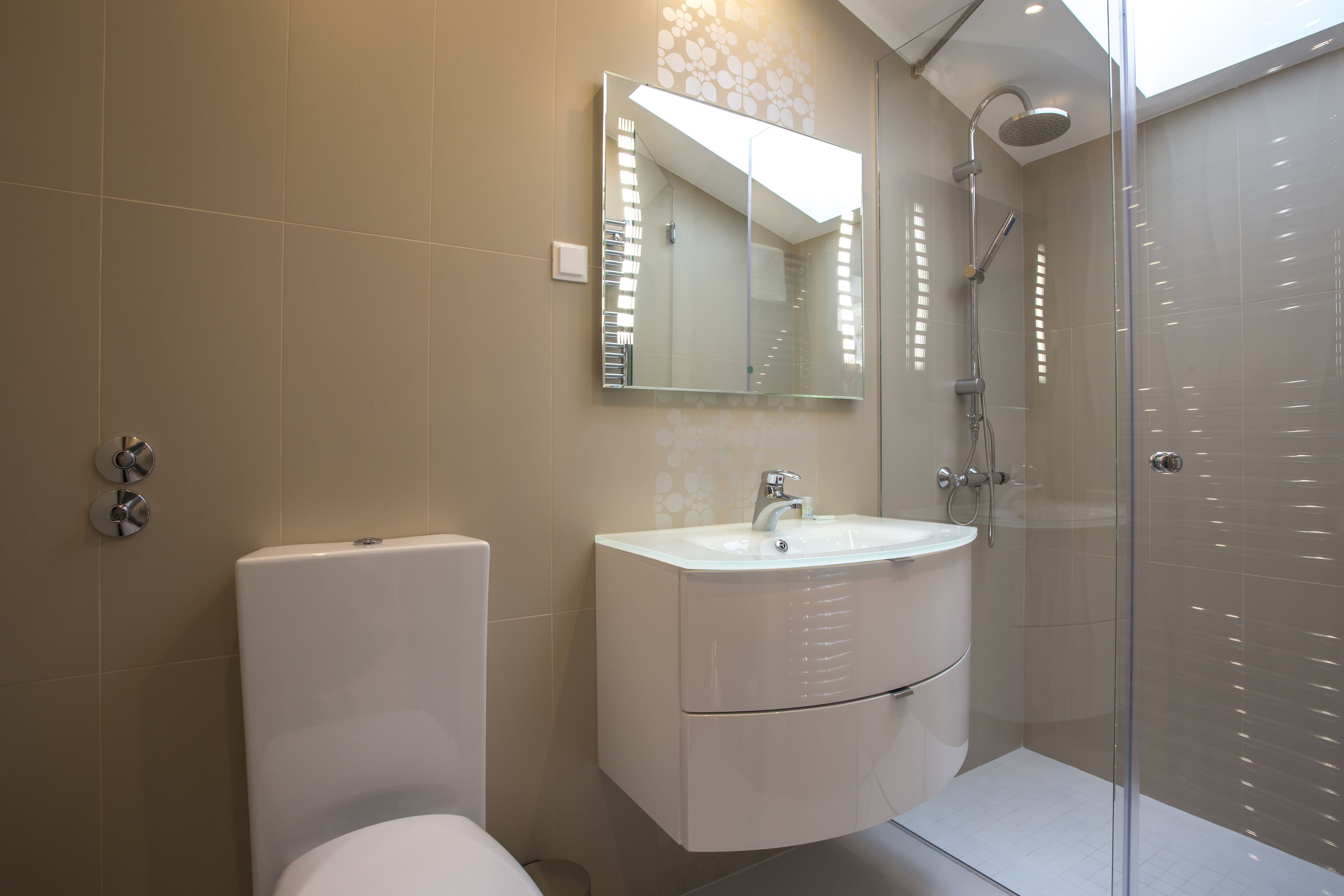 A modern bathroom with a toilet, a sink, and a shower.