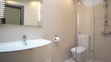 Ein modernes Badezimmer mit einer Duschkabine, einem weißen Waschbecken und einer Toilette.
