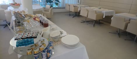 Un buffet proposant une variété d'aliments et de boissons, notamment des yaourts, des fruits et un assortiment de boissons.