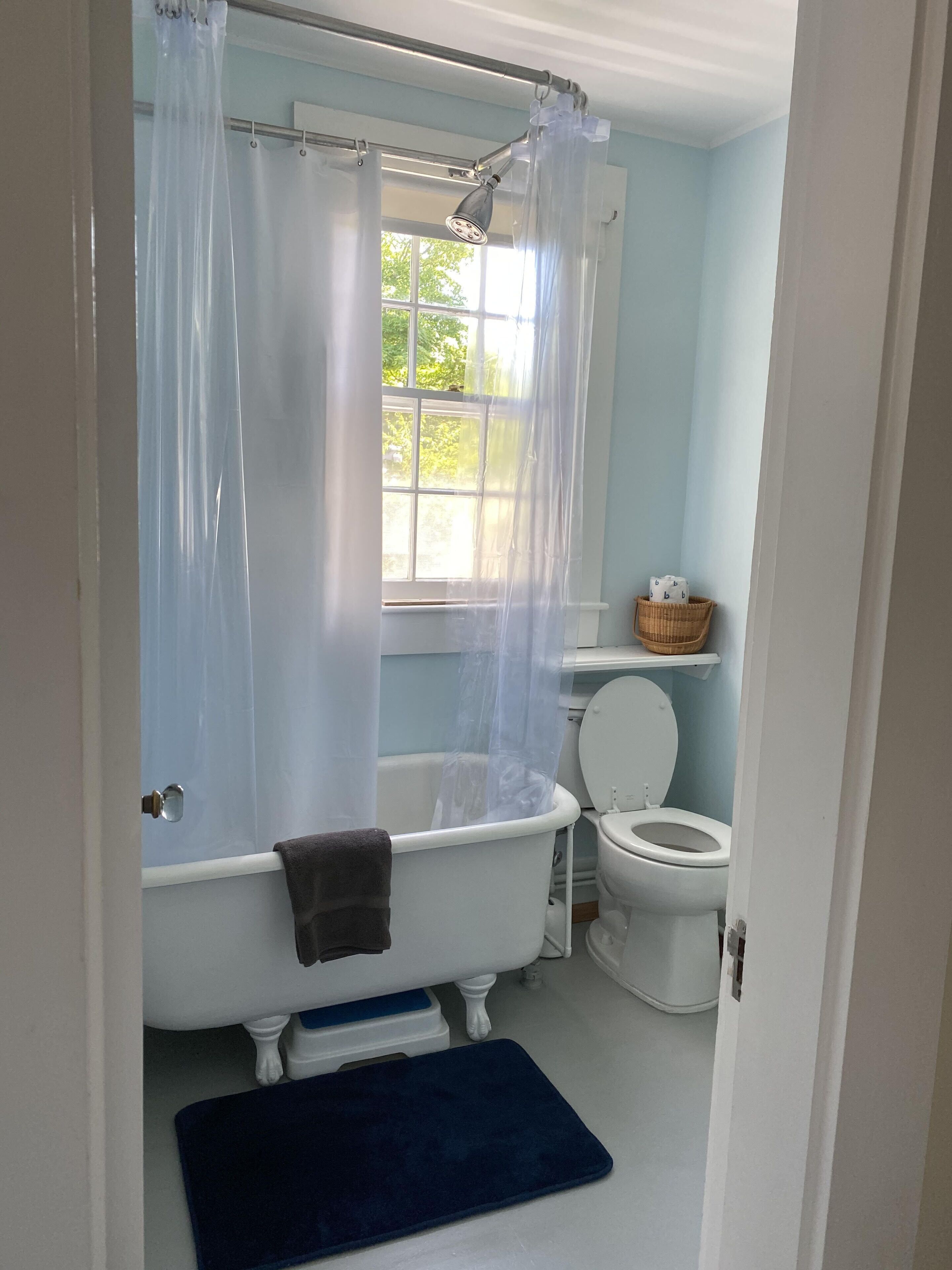 A bathroom with a bathtub, toilet, and a window.