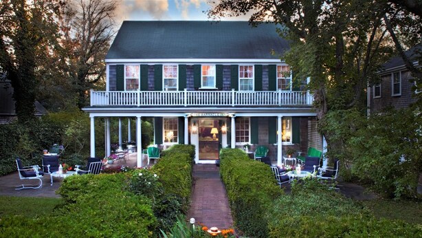 A two-story building with a covered porch and outdoor seating area.