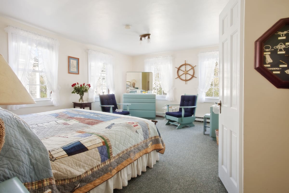 A bedroom with a bed, dresser, chairs, and a large mirror.