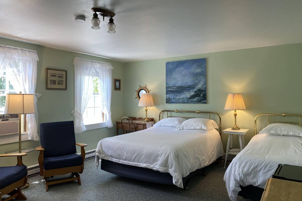 A hotel room with a large bed, two bedside tables, a chair, a desk, and a ceiling fan.