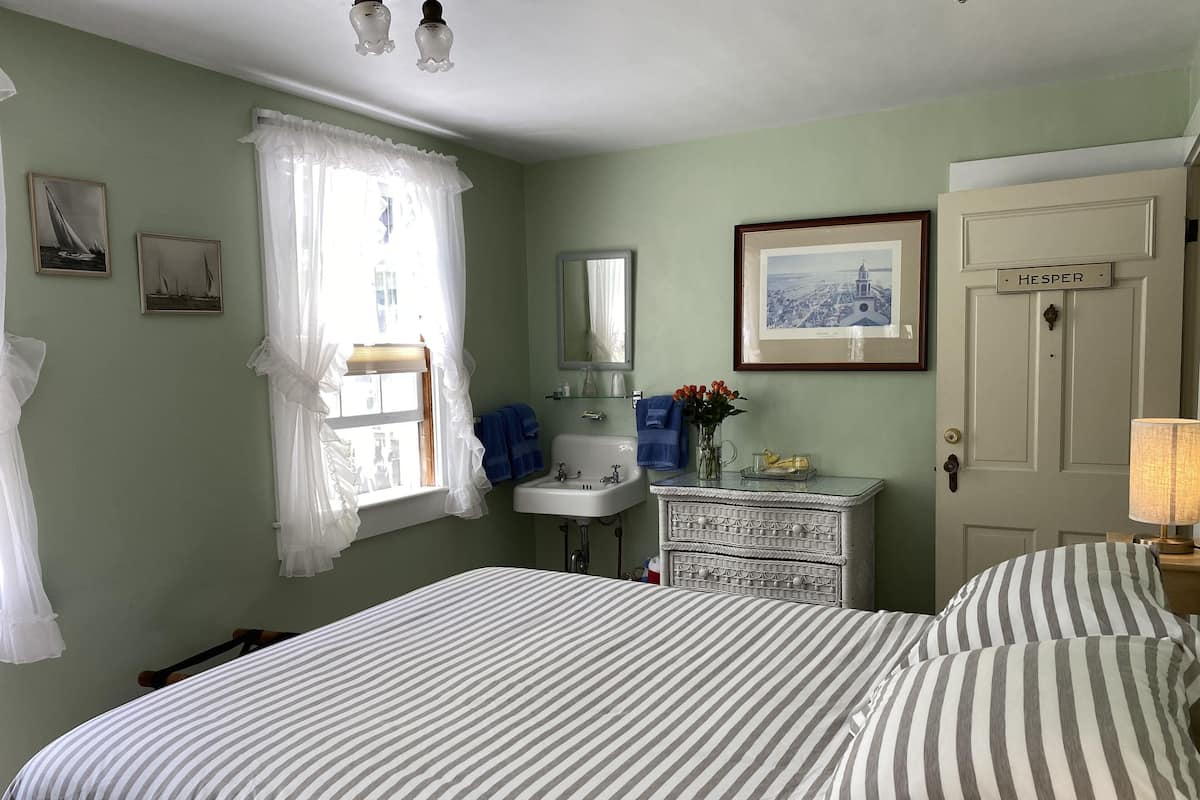 A bedroom with a bed, a dresser, a vanity, and a door labeled "HESPER".