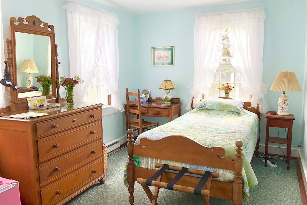 A bedroom with a wooden bed, a dresser, a chair, and a desk.