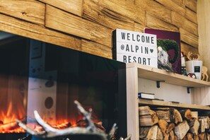 A sign reading "WELCOME @ALPIN RESORT" above a fireplace with logs. - Alpin Resort Austria (Bichlbach)