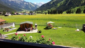 A rural setting with a small wooden cabin and a dining area with tables and chairs. - Alpin Resort Austria (Bichlbach)