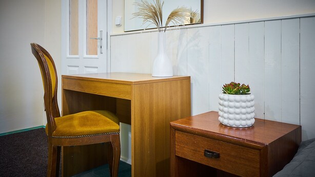 A wooden desk with a chair, a small white cabinet, and a mirror on the wall. - Penzion Weber (Cesky Krumlov)
