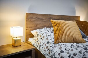 Una cama bien tendida con ropa de cama floral, un cabecero de madera y una lámpara de noche.