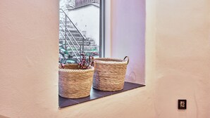 Una ventana con dos cestas tejidas sobre un alféizar negro, con vista a una escalera de piedra y un edificio.