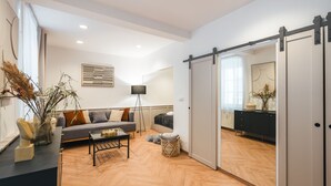 Una sala moderna con sofá, mesa de centro y puerta corrediza que da a otra habitación.